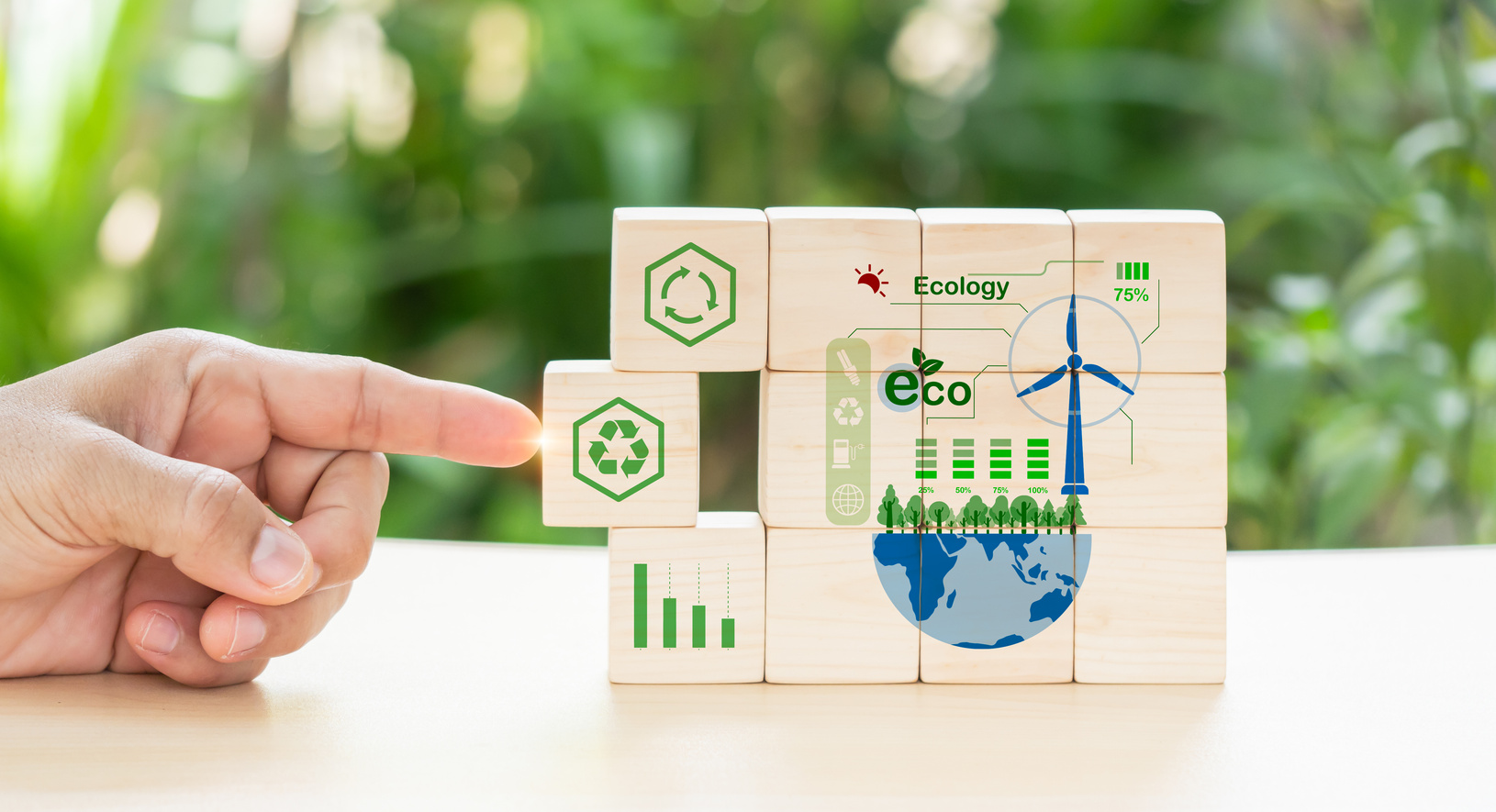 Hand put wooden cubes; the symbols of circular economy on green background.Circular economy concept, recycle, environment, reuse, manufacturing, waste, consumer, resource. Sustainable development.